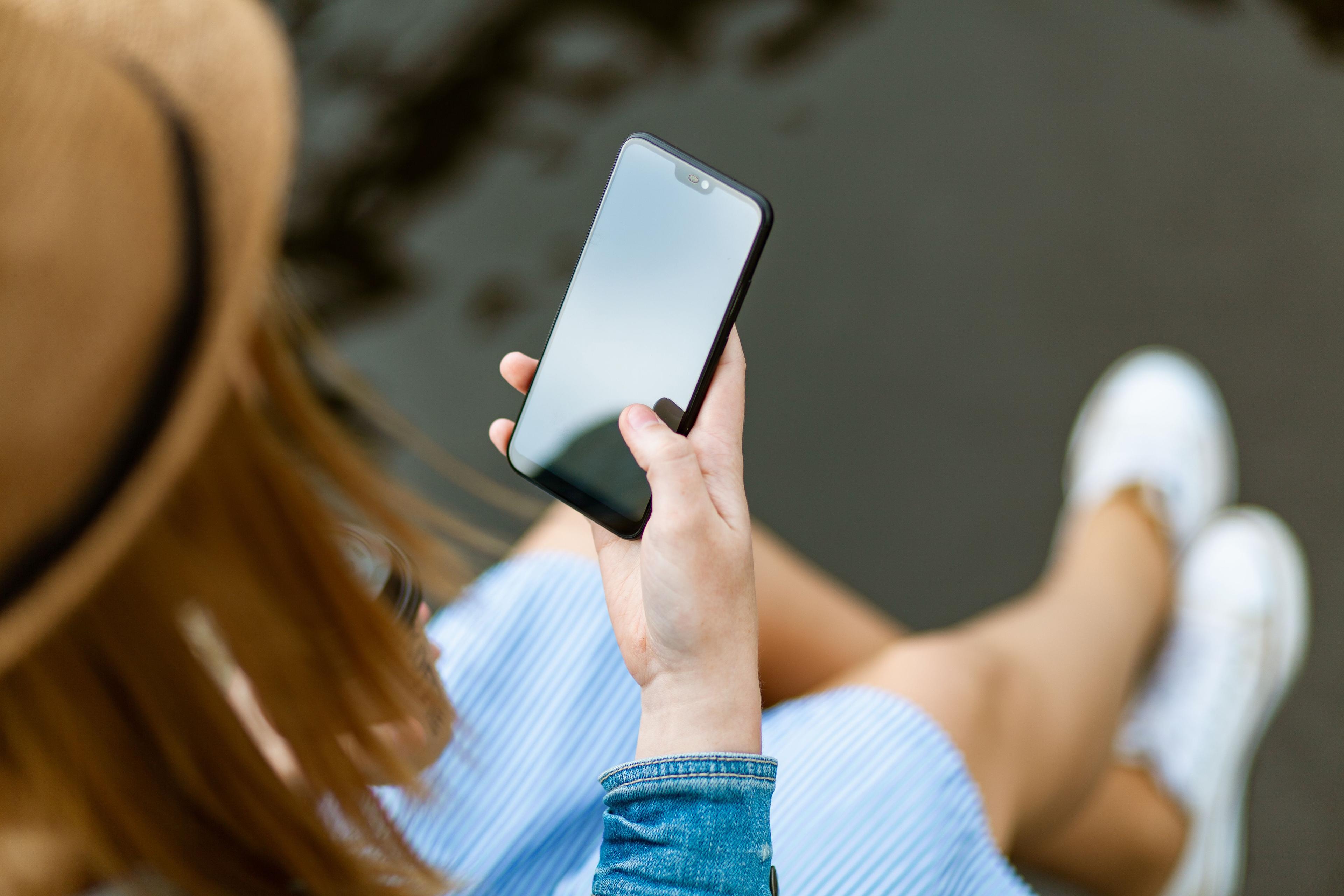 Mitarbeiterin beantragt Urlaub digital über Smartphone-App im Büro Mitarbeiterin beantragt Urlaub digital über Smartphone-App im Büro
